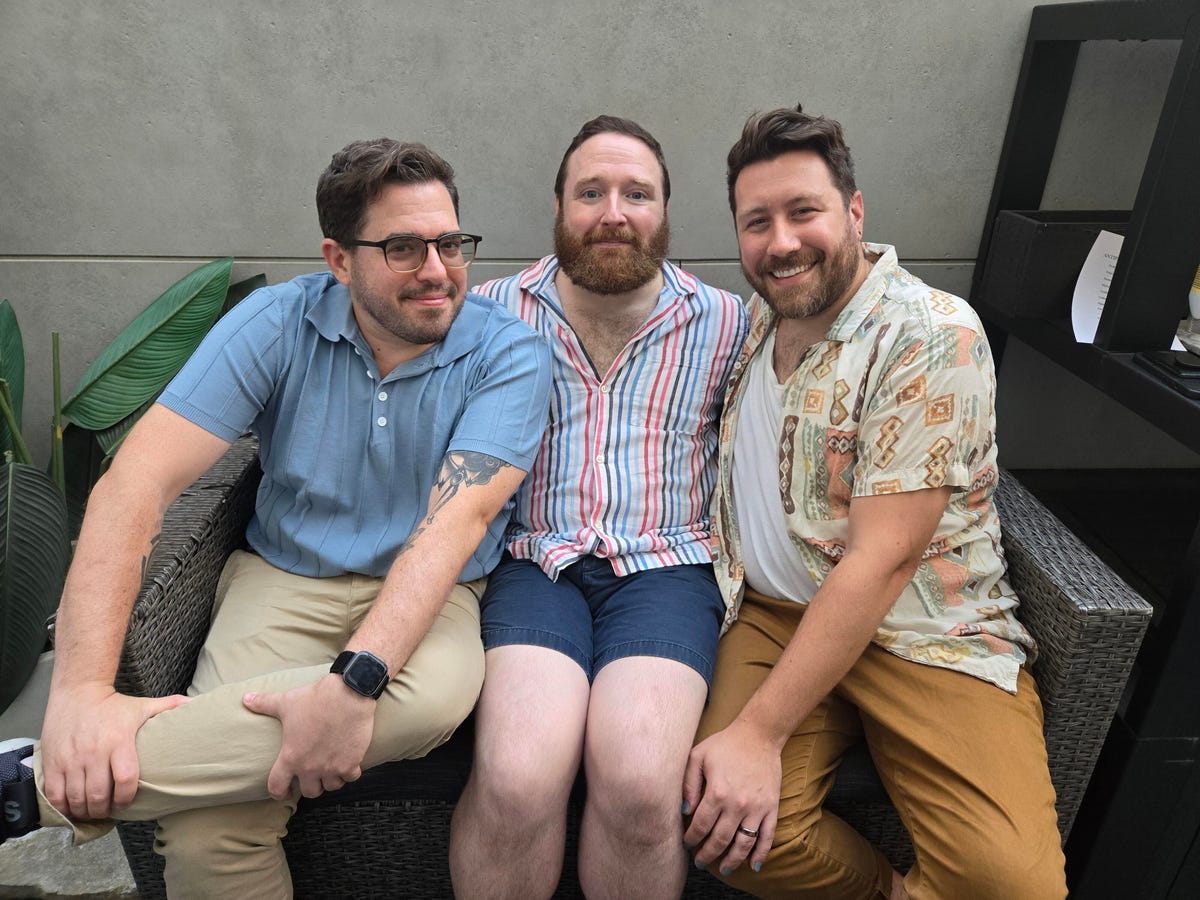 Three men sitting on a couch outside