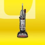 Hoover Wind Tunnel bagless upright vacuum with red accents on a bright yellow background