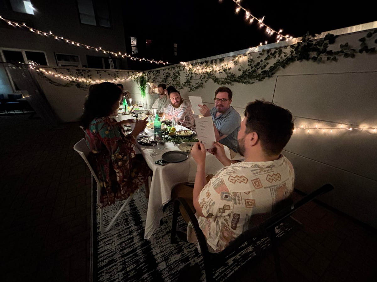 A photo of people sitting around a table outside