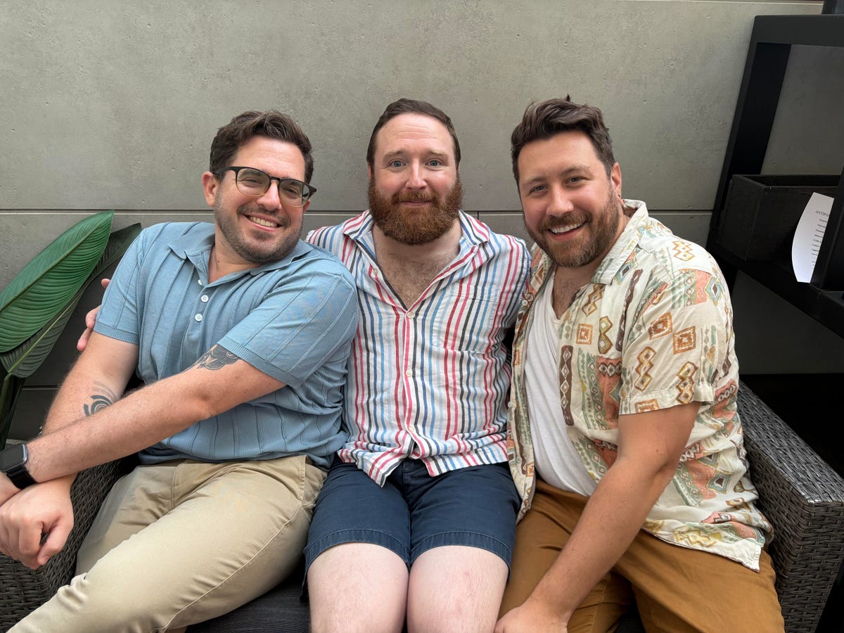 Three men sitting on a couch outside