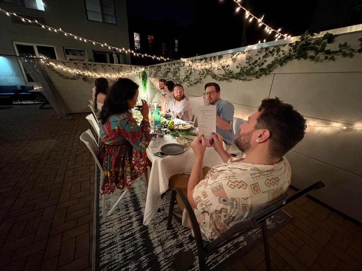 A group of people sitting around a table outside at night.