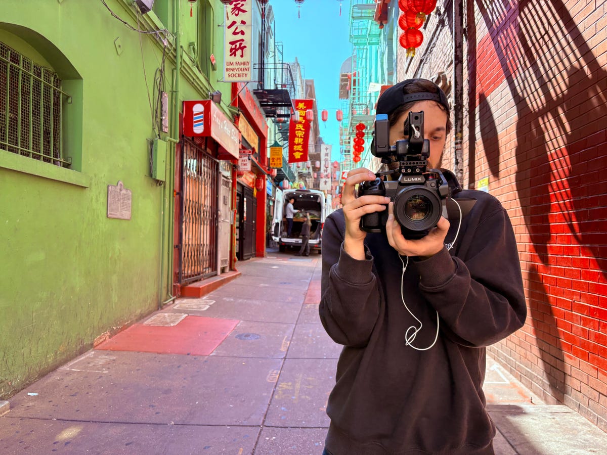 A photo of a man with a camera in a colorful alleyway