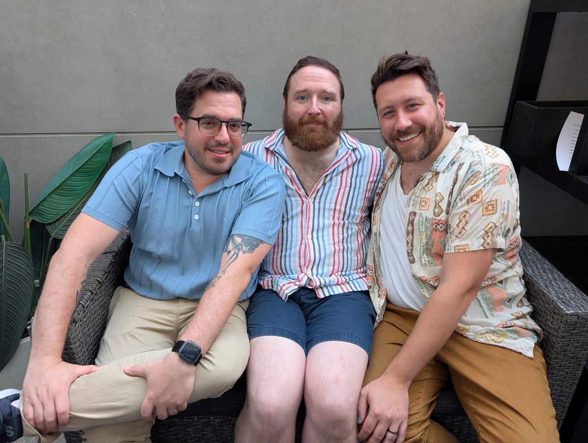 A photo of three men on a couch outside