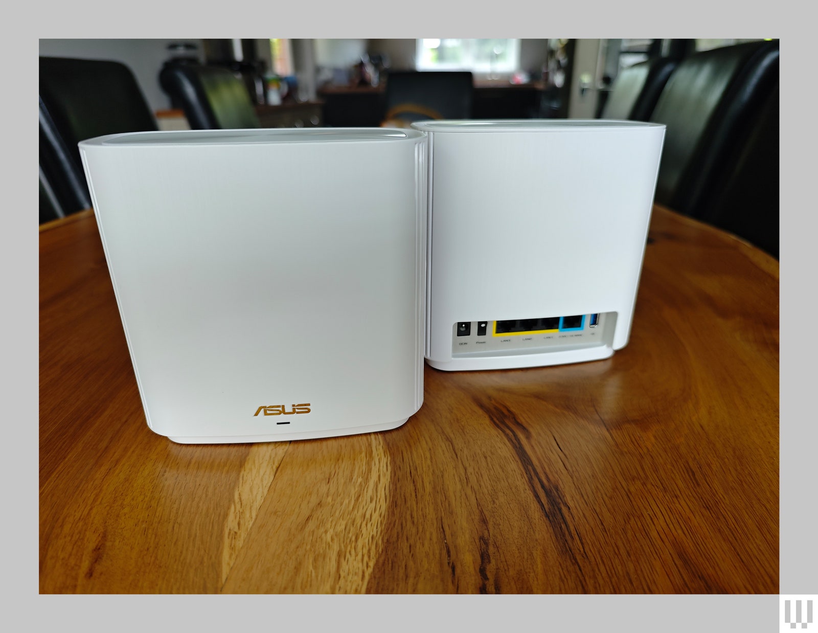 2 white rectangular wifi router devices one facing front and the other backwards showing the ports