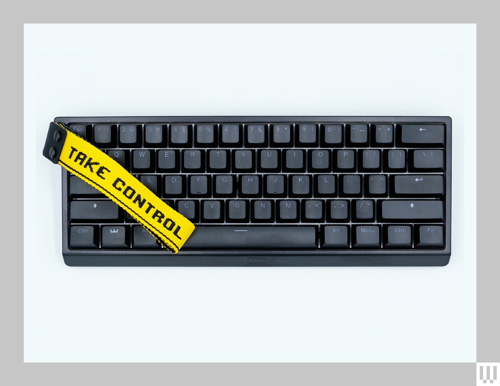 Black computer keyboard with a bright yellow fabric strap overlapping one side that reads take control