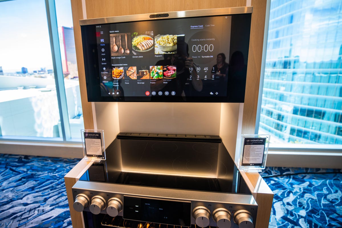 A microwave with a large display showing food options, mounted above an induction range.