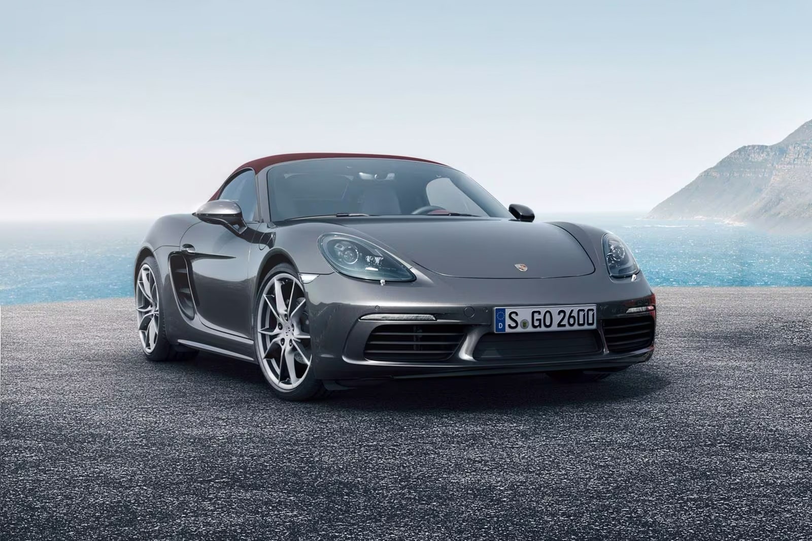 A grey sports car with the ocean behind