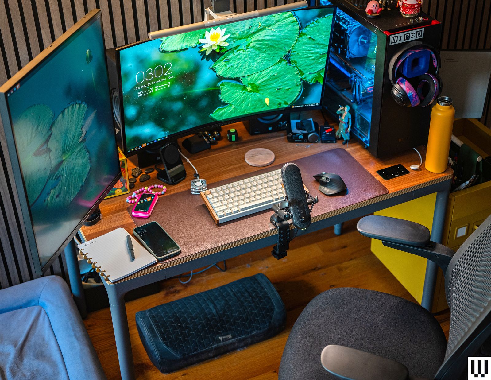 Front view of Branch Four Leg Standing Desk with computer monitors keyboard microphone and other work items on top