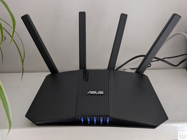 Asus RT-BE58U, a black angular wi-fi router with 4 antennae sticking up from the back