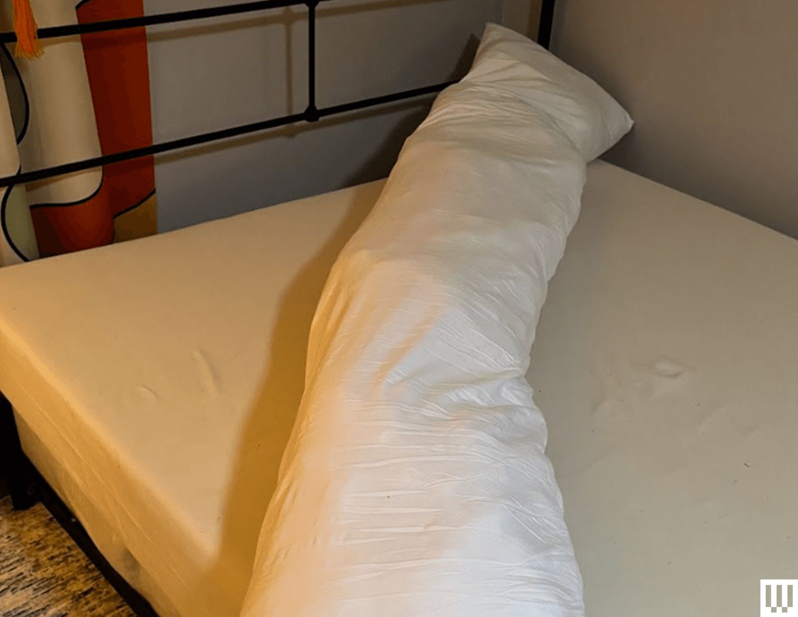 Long rectangular body pillow on top of a mattress