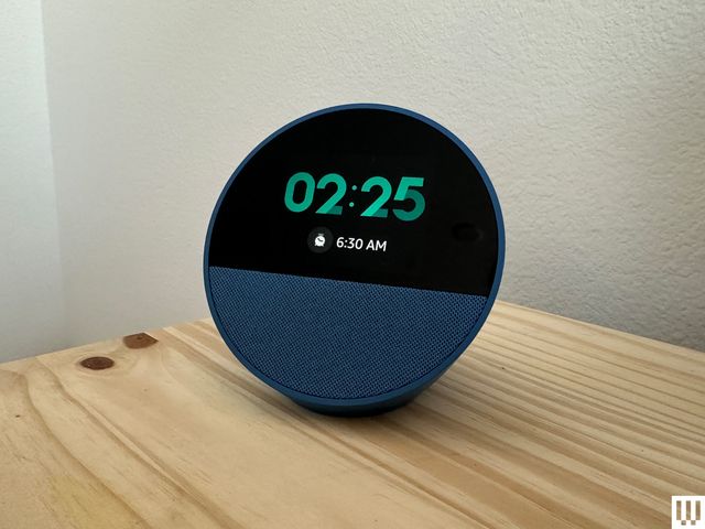 Echo Spot 2024 edition, a semi-sphere device with a screen on the front, displaying the current time as well as the time the alarm is set for.