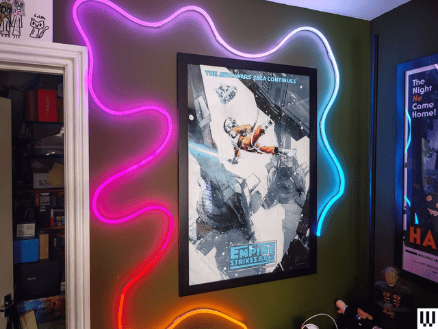 Wavy tube of neon lights attached to a wall, swirling around a poster