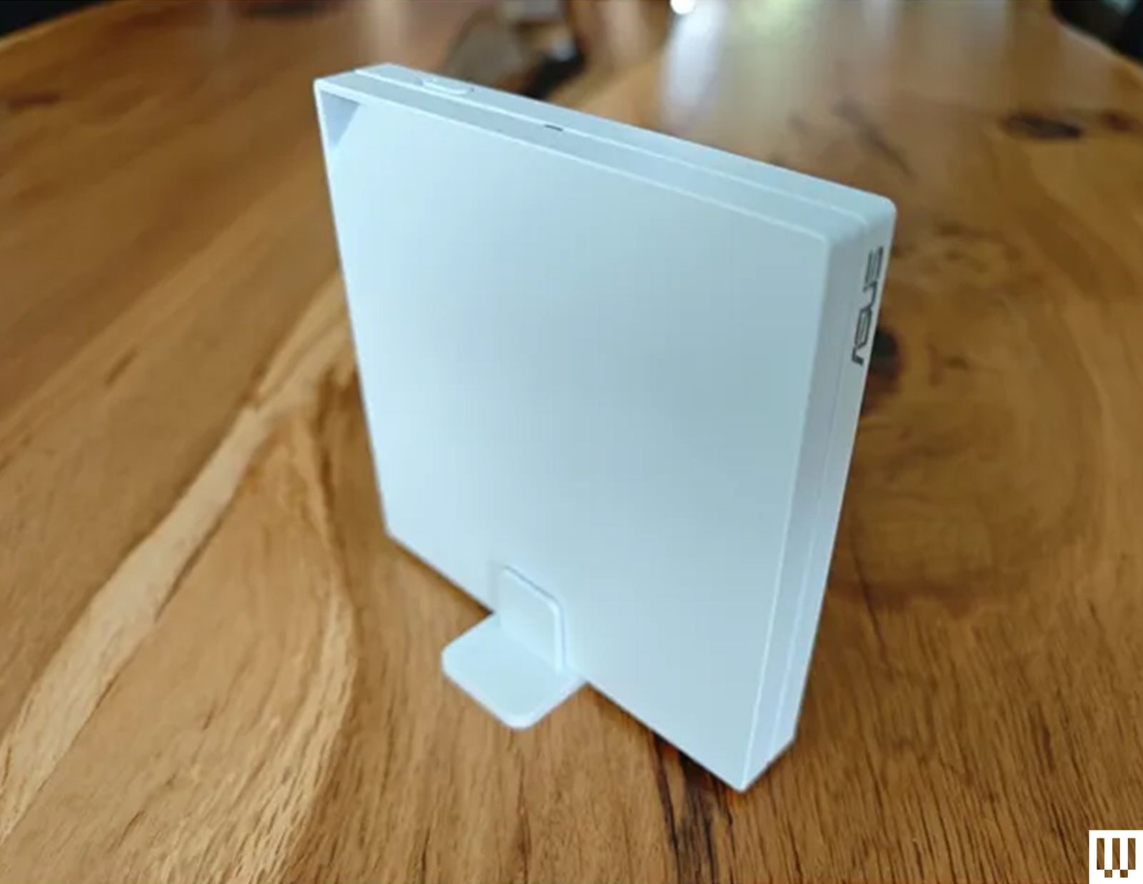 Side view of slim white wifi router device sitting on long wooden table