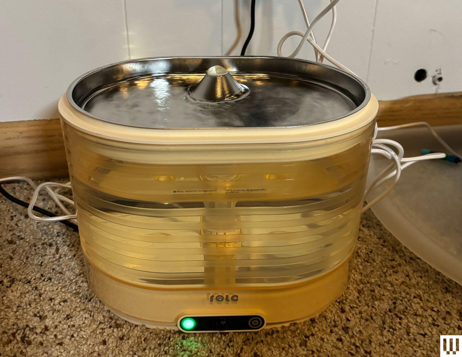 ROLA Smart Pet Water Fountain an ovalshaped device with a yellowtinted seethrough center and metallic pan on top where...