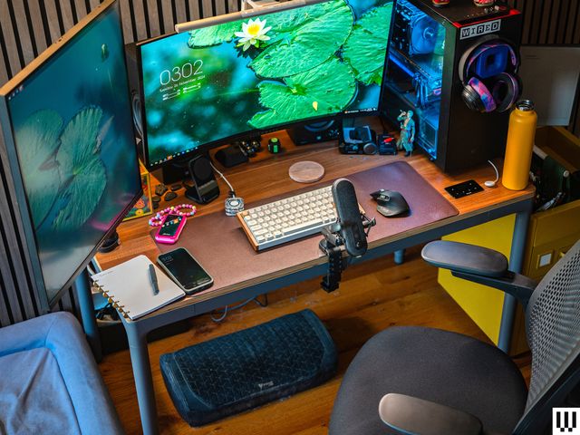 Front view of Branch Four Leg Standing Desk with computer monitors, keyboard, microphone and other work items on top