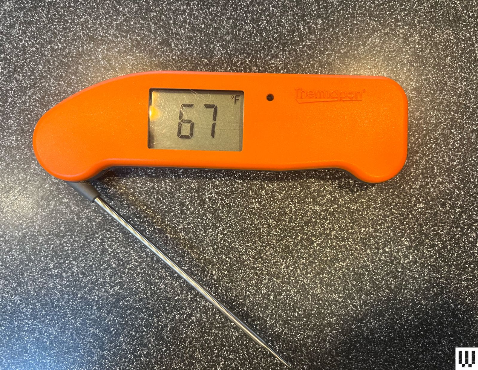 Overhead view of Thermo Works Thermapen One an orange food thermometer with a small digital screen and long silver rod...