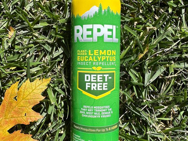 Repel Plant-Based Lemon Eucalyptus Insect Repellent, a green aluminum can with spray top, laying in a patch of grass beside an orange leaf