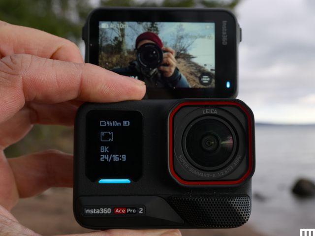 Front view of Insta 360 Ace Pro 2 Action Camera, a black square camera with small lens, digital screen, and flip-up screen.