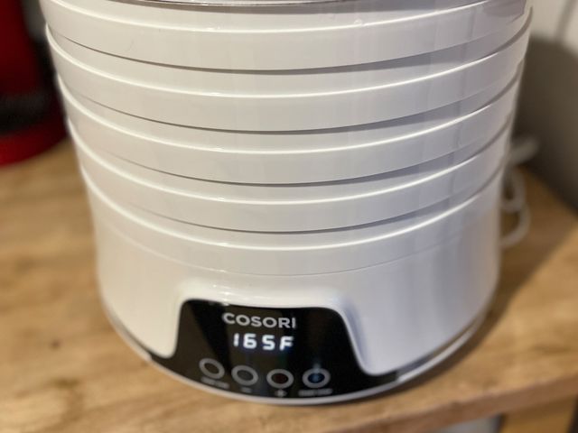 White cylindrical culinary device with a clear lid sitting on a wooden surface