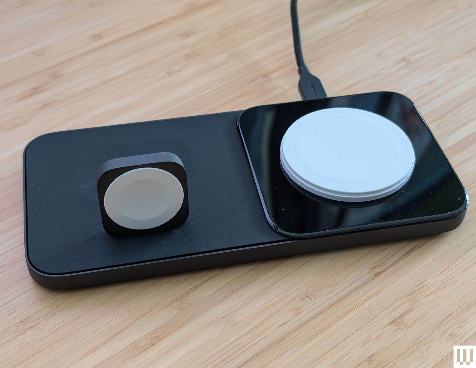 Nomad Base One Max a flat black panel with and upright square to wrap a watch around and a flat disc to place a mobile...