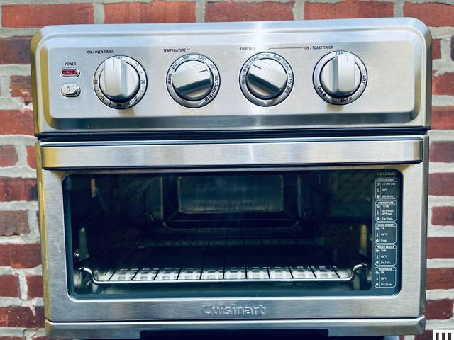 Cuisinart TOA-70 Air Fryer Oven and Grill sitting on a white table in front of a brick wall