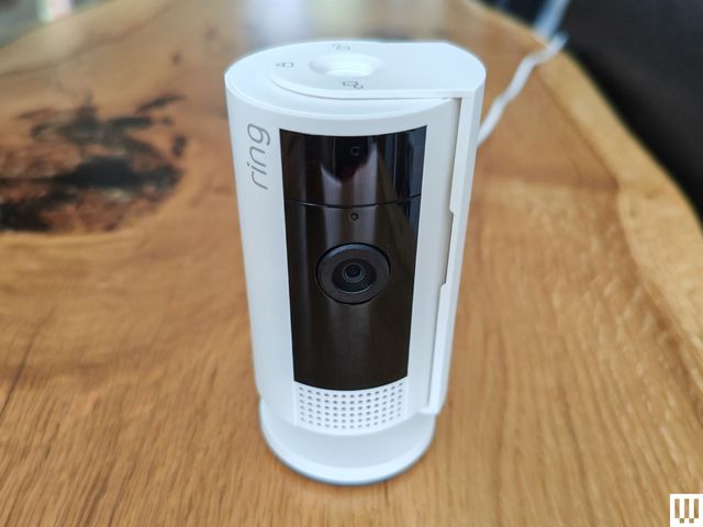 Rectangular cylindrical security camera sitting on a wooden surface