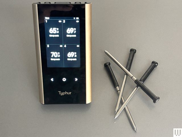Typhur Sync Gold Quad, a rectangular device with a small screen, beside small silver rod meat thermometers 