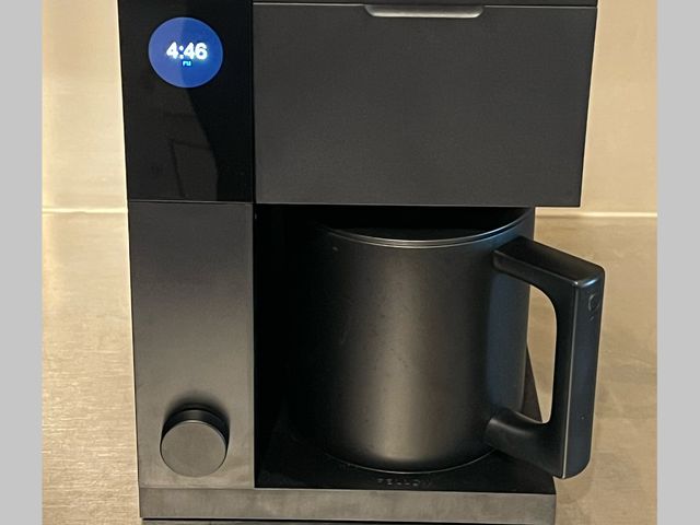 Front view of the Fellow Aiden Precision Coffee Maker, a black, rectangular coffee maker with small digital screen on the left and a large black coffee pot